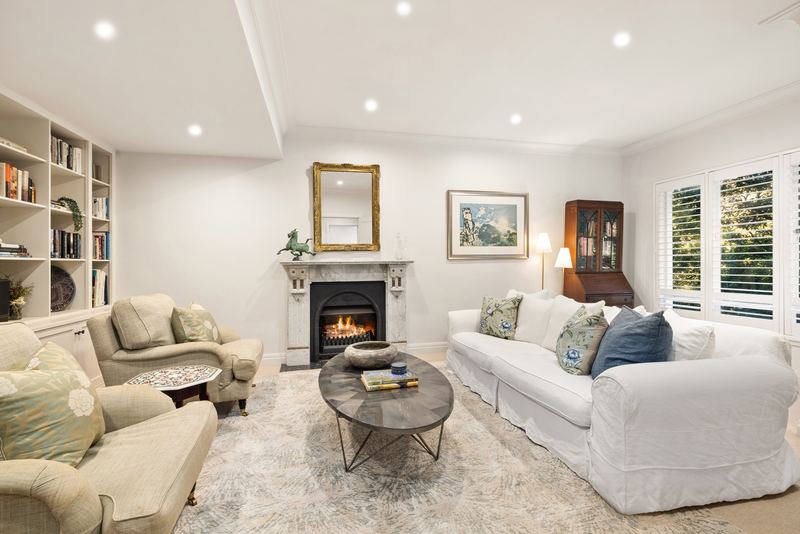 Formal lounge with a lit marble fireplace, built-in bookshelves and plantation shutters