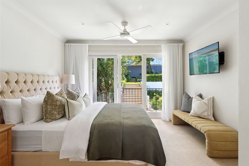 Bedroom with tufted bedhead and French doors opening to a balcony