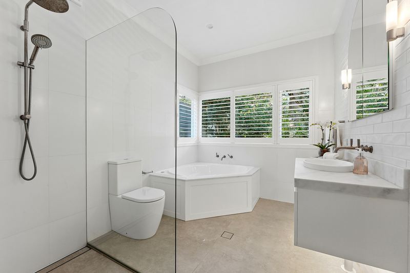 Bathroom with corner spa bath, frameless shower and shuttered windows